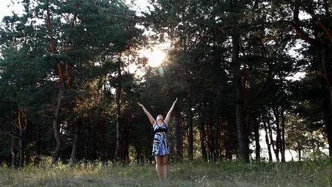 Woman performs deep breathing exercises among the tall pines on a sunny day Stock Footage 100181418