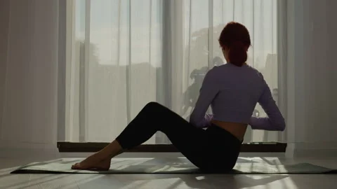 Woman performs dumbbell exercises on mat in bright living room Stock Footage 309398317