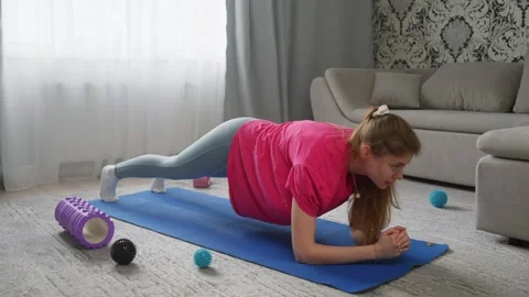 A woman performs a dynamic plank exercise while exercising at home. Stock Footage 273572072