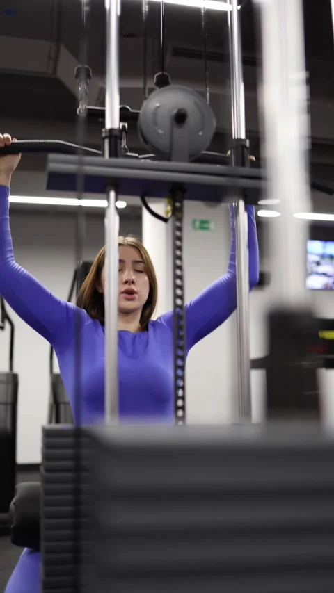 Woman performs first cable machine exercise alone in gym Stock Footage 328253751