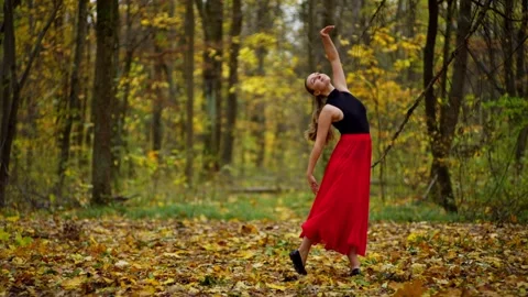 A woman performs her dance performance in the middle of a large autumn forest. Stock Footage 264582333