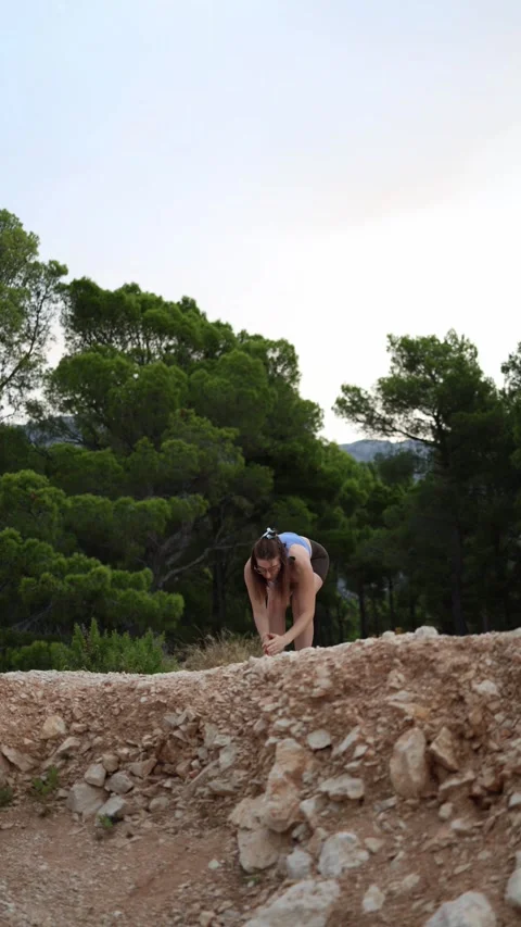 Woman performs standing forward fold yoga stretch outdoors Stock Footage 341317955