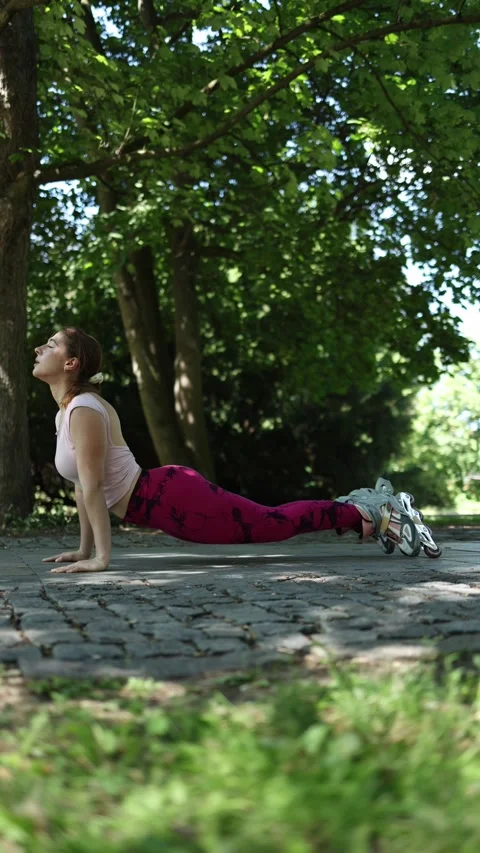 Woman performs upward facing dog yoga pose while wearing rollerblades Видео 341476704