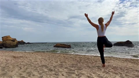 Woman performs yoga pose on sandy beach. Harmony and mindfulness concept Vídeo Stock 336596549