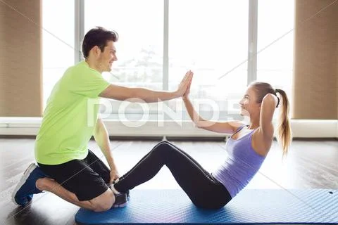 Woman with personal trainer doing sit ups in gym Stock Photos