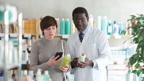 Woman in pharmacy scans QR code on antidandruff shampoo. African man pharmacist Video stock 310965641
