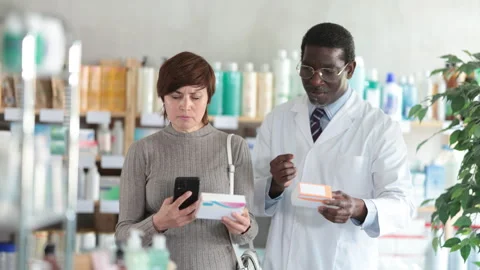 Woman in pharmacy scans QR code on pills, studies item in detail, collects Stock Footage 313873857