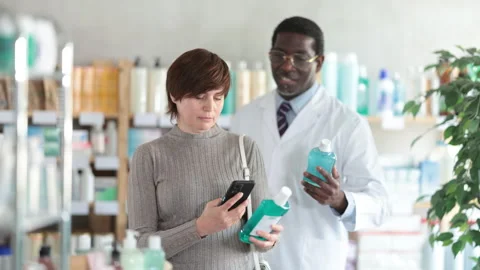 Woman in pharmacy scans QR code on mouthwash, studies item in detail, collects Stock Footage 313876457