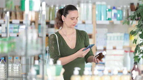 Woman in pharmacy scans QR code on expectorant syrup Stock Footage 314243722