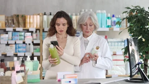 Woman in pharmacy scans QR code on shampoo, senior woman pharmacist in Stock Footage 316581888