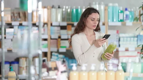 Woman in pharmacy scans QR code on shampoo product Stock Footage 317999287