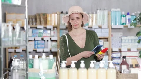 Woman in pharmacy scans QR code on sunscreen cream Stock Footage 323911412