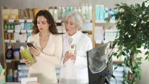 Woman in pharmacy scans QR code on shampoo, senior woman pharmacist in Stock Footage 325767232