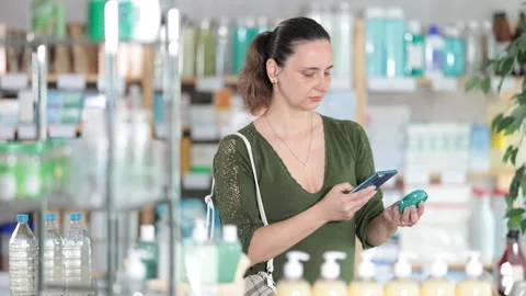 Woman in pharmacy scans QR code on dry rouge cosmetic Stock Footage 326314777