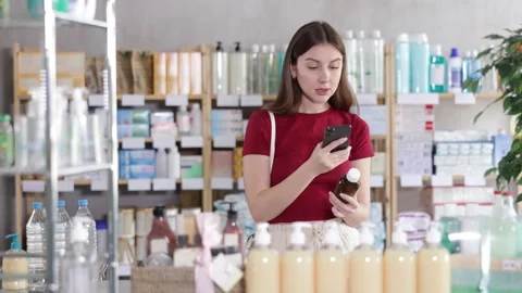 Woman in pharmacy scans QR code on antitussive syrup Stock Footage 329392823