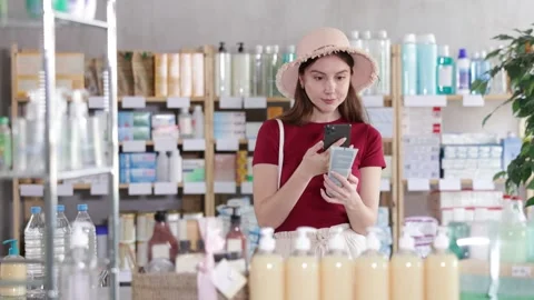 Woman in pharmacy scans QR code on sunscreen cream Stock Footage 347257971