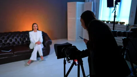 Woman with phone in hand checking the camera in tripod. Lady wearing white suit Stock Footage 331252686