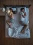 The woman with phone lay on the bed near husband. view from above Photo