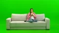 The woman phones on the sofa on the green background 4k or 4k+ Resolution