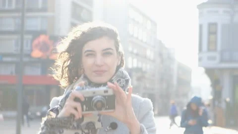 Woman photographing with a retro film camera in the city Stock Footage