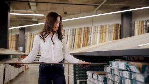 Woman picking laminate board for future floor. Customer choosing texture Stock Footage 265899010