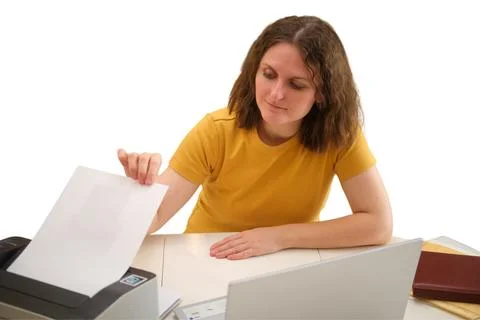 Woman picking up printed document from printer in office. Employee working at Stock Photos
