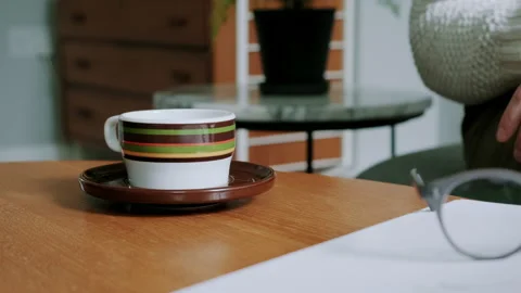 Woman picking up tea cup while sitting down Video stock 130644199