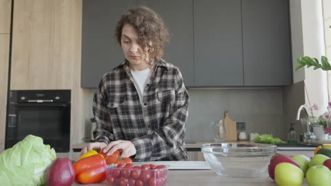 Woman Picking Up Tomato And Examining Vegetables On Table In Bright Kitchen 스톡 동영상 308455053