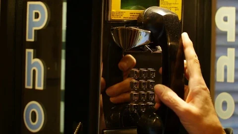 Woman picks up and dials from public telephone payphone - close up Stock Footage