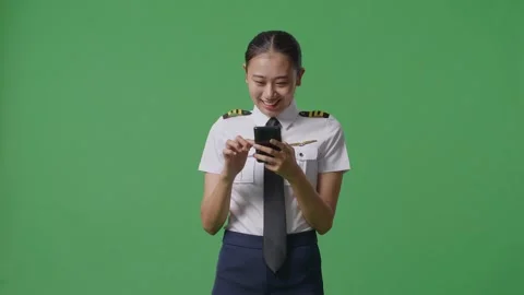 Woman Pilot Smiling And Using Smartphone While Standing In The Green Screen Stock Footage 251641653