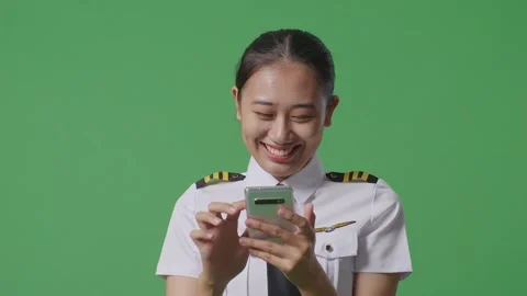 Woman Pilot Smiling And Using Smartphone While Standing In The Green Screen Stock Footage 251643676