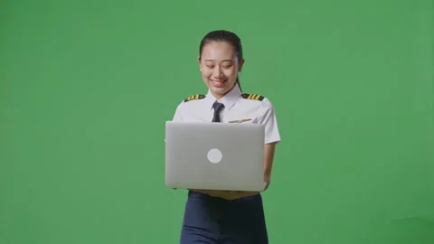 Woman Pilot Smiling And Using A Laptop While Walking In The Green Screen Stock Footage 251685299