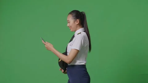 Woman Pilot Smiling And Using Smartphone While Walking In The Green Screen Stock Footage 251686568