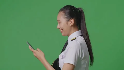 Woman Pilot Smiling And Using Smartphone While Walking In The Green Screen Stock Footage 251686795