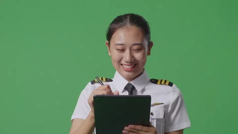 Woman Pilot Taking Note On A Tablet While Standing On Green Screen Background Stock Footage 251644172