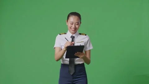 Woman Pilot Taking Note On A Tablet While Walking In The Green Screen Background Stock Footage 251685191