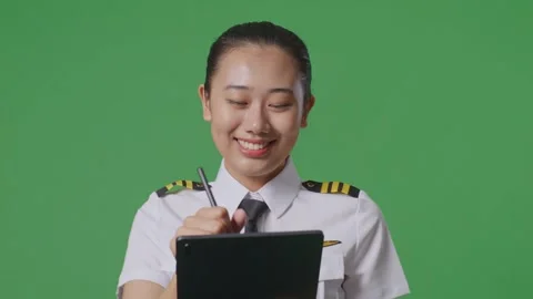 Woman Pilot Taking Note On A Tablet While Walking In The Green Screen Background Stock Footage 251685795