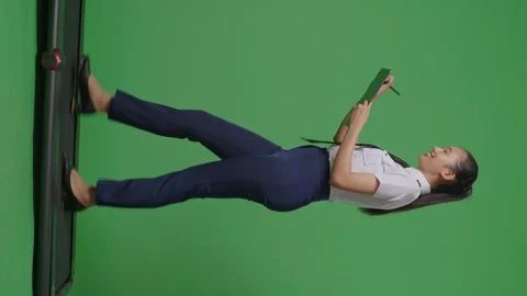 Woman Pilot Taking Note On A Tablet While Walking On Treadmill On Green Screen Stock Footage 251686431
