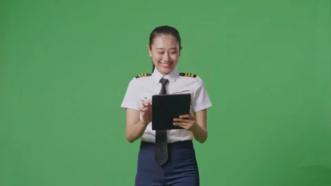Woman Pilot Using A Tablet While Walking In The Green Screen Background Studio Stock Footage 251685170