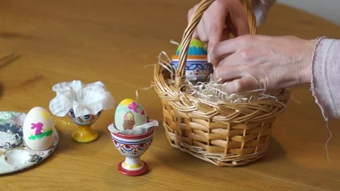 Woman Placing Diverse Painted Easter Eggs into Gift Basket Stock Footage 329248217
