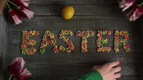 Woman is placing eggs on easter sign decorated with tulips Stock Footage 73380039