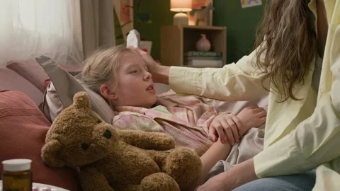 Woman Placing Mug on Bedside Table and Kissing Sick Daughter Stock Footage 335475645