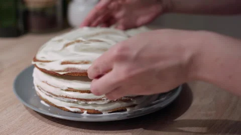 Woman placing a sponge layer on a cake, woman assembling a cake Stock Footage 302099525