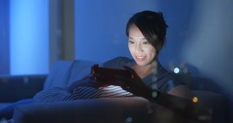 Woman play game on cellphone inside home at night with window reflection Stock Footage 107391753