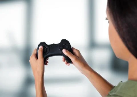 Woman playing with computer game controller with bright blurred background Stock Photos
