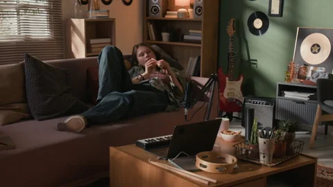 Woman Playing Flute Lying Back on Couch in Home Recording Studio Stock Footage 335398846