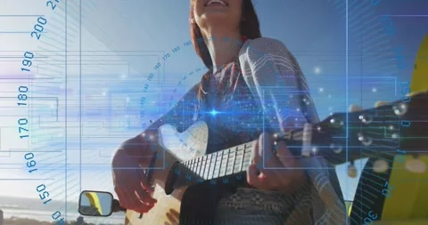 Woman playing guitar seaside, pullback revealing blue HUD marking chords for Stock Footage 333964971