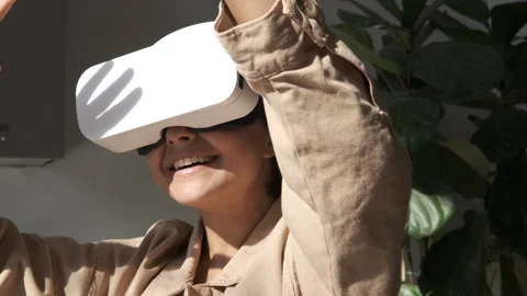Woman playing using VR goggles at home. Girl wearing virtual reality headset. Stock Footage 250403179