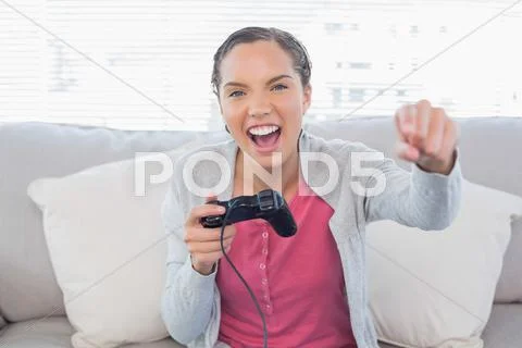 Woman playing video games on sofa and winning Stock Photos