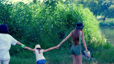 A woman plays with her daughters while cleaning up trash on a riverbank Stock Footage 340463302